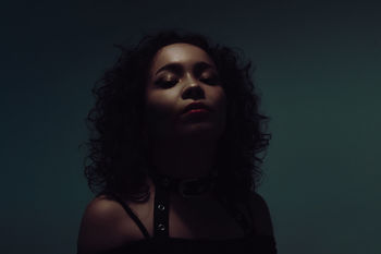 CLOSE-UP PORTRAIT OF WOMAN AGAINST GRAY BACKGROUND