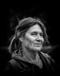 Close-up portrait of smiling woman against black background