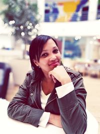 Portrait of smiling woman sitting at table in mall