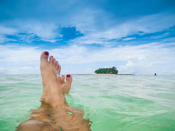 Low section of person in sea against sky