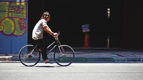 Side view of man riding bicycle on street in city