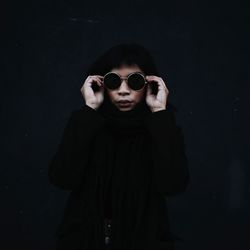 Portrait of woman standing against black background