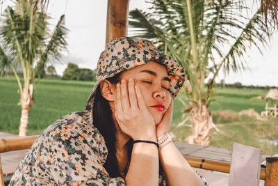 Portrait of young woman sitting on palm tree