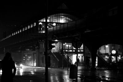 People on illuminated bridge in city at night