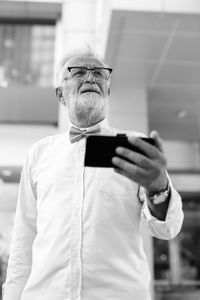 Midsection of man holding smart phone while standing outdoors