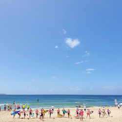 Group of people on beach against blue sky