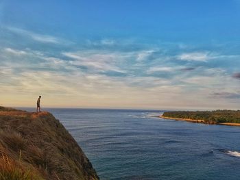 Man looking at sea against sky during sunset