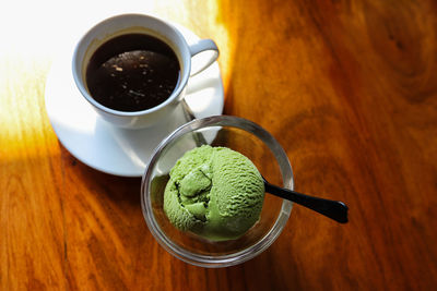 High angle view of coffee cup and green tea ice cream on table