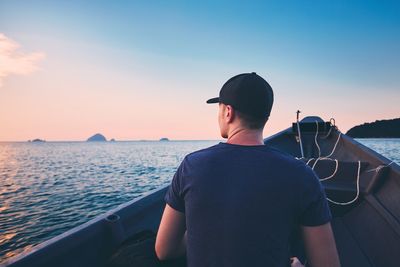 Rear view of man traveling in boat on sea during sunset