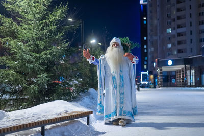 Russian santa claus carries a christmas tree outdoors