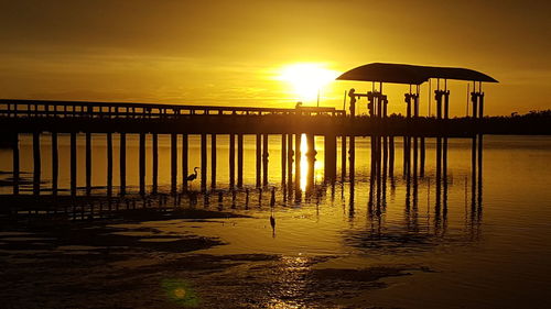 Silhouette pier on beach against sky during sunset