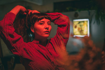 Dark-haired female model in vintage clothing and make-up in a dark bar with red light.