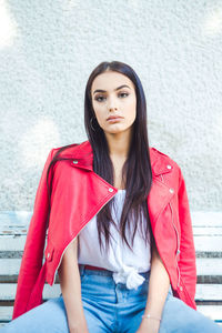 Portrait of beautiful woman sitting against wall