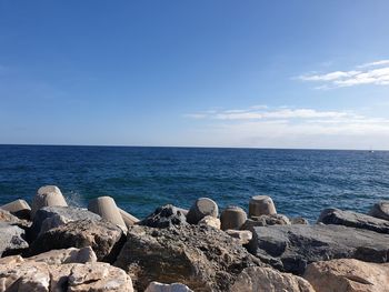 Rocks by sea against blue sky