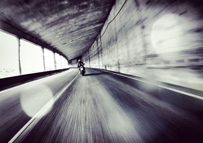 Blurred motion of person riding motorcycle in tunnel