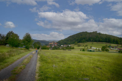 Road amidst field against sky