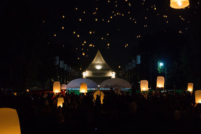 People on illuminated street against buildings at night