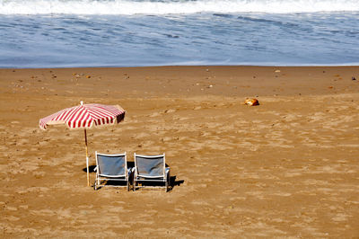 Deck chairs and parasol on sea shore at beach