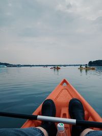 Rear view of man sitting on boat in lake against sky