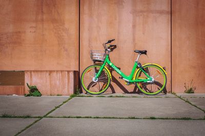 Bicycle parked on footpath against wall