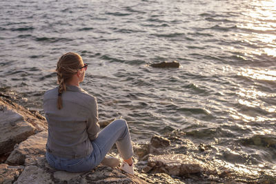 Back view of woman sitting by the sea