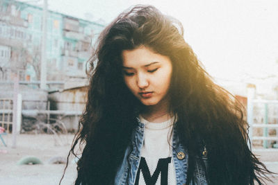 Close-up of beautiful woman standing with eyes closed against buildings