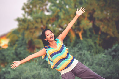 Smiling young woman with arms raised