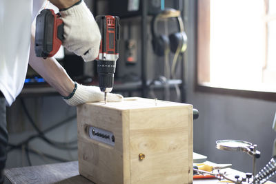 Diy work at home, man screwing speaker cabinet, close up.