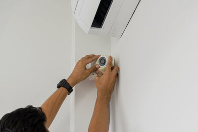 Cropped hand man installing cctv on wall at home