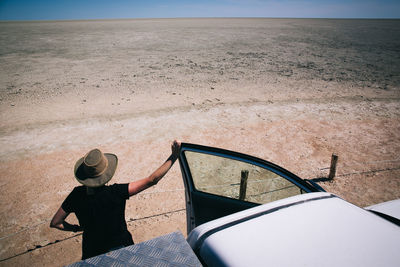 High angle view of person standing by off-road vehicle in desert on sunny day