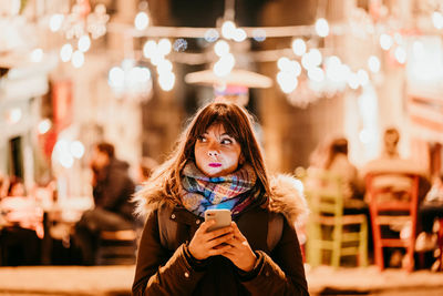 Portrait of young woman using mobile phone in winter