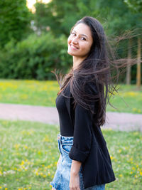 Portrait of young woman standing on field