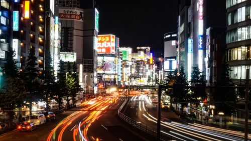 Light trails on city street amidst buildings at night