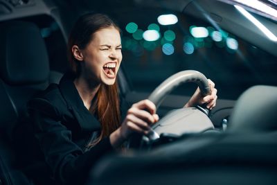 Angry young woman driving car at night