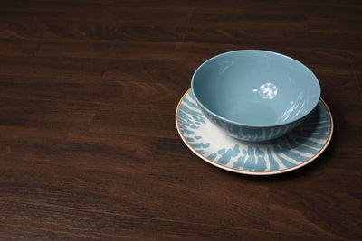 Close-up of empty bowl and saucer on wooden table