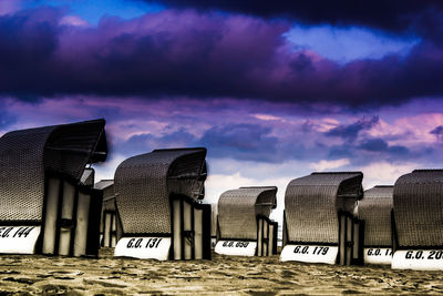 Hooded beach chairs against cloudy sky