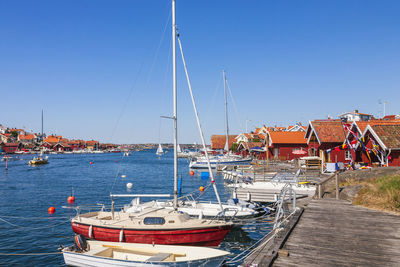 Boats moored at harbor against clear blue sky