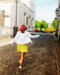 Full length rear view of carefree teenage girl walking on street in city