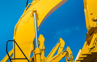 Low angle view of yellow crane against clear blue sky