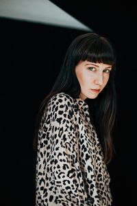 Portrait of woman standing against black background