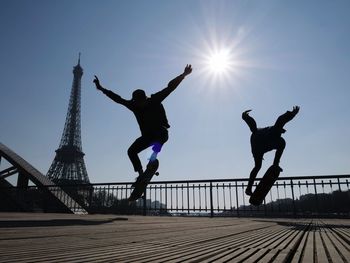 Low angle view of skateboarding on boardwalk against eiffel tower and sky during sunny day