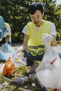 Young male volunteer picking up plastics at park