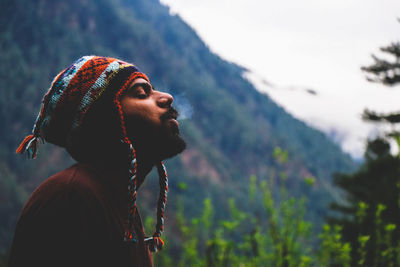 Man exhaling fog against mountain