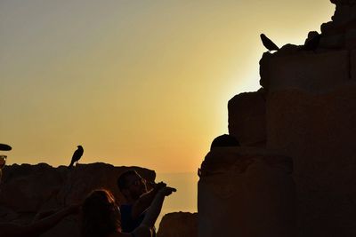 Silhouette people photographing against sky during sunset