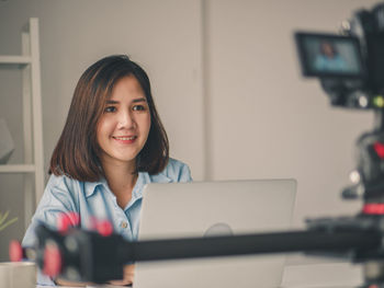 Portrait of a smiling young woman using phone