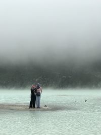 Friends standing on shore against sea