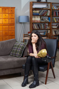 Young woman sitting on chair at home