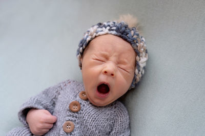 Cute baby yawning while lying on bed at home