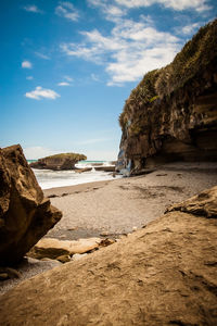 Rock formations at beach against sky