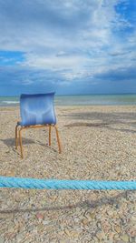 Chair on beach against sky